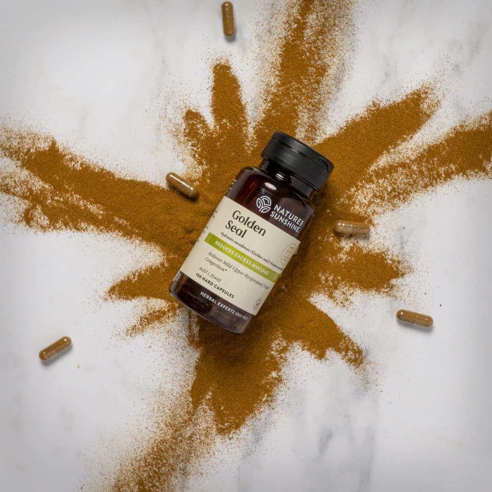 Bottle of Nature's Sunshine Golden Seal with an explosion of golden seal powder and capsules around it.